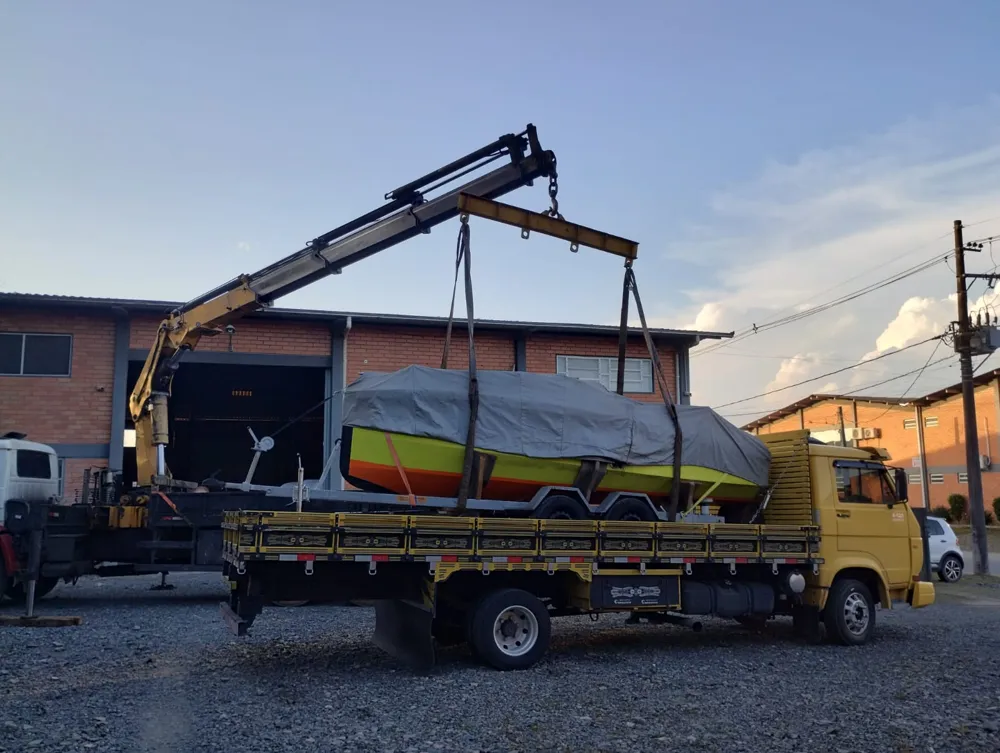Barco sendo içado de carreta por caminhão munck