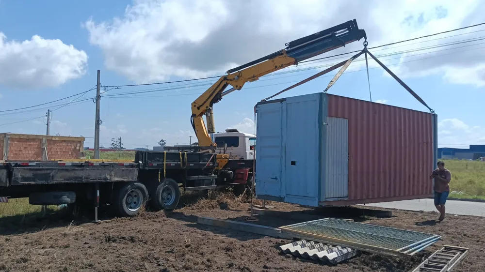 Container sendo içado e posicionado por caminhão munck